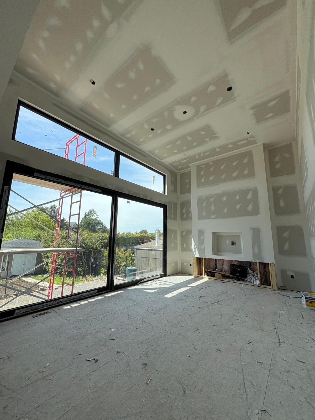 Tall vaulted room with taped drywall and fireplace