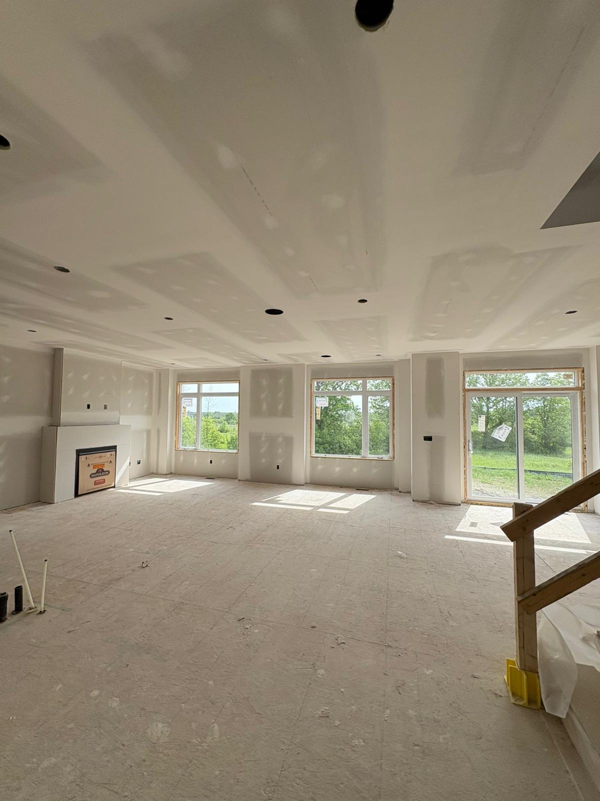 Open living area with taped ceiling and large windows